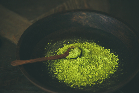 Japanese Matcha green tea powder in dark wooden bowl with spoon, selective focus, copy space, horizontal composition. Clean eating, healthy, diet food conceptの写真素材