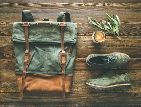 Flat-lay of womans fall accessories and coffee. Haki suede leather oxford boots, large green backpack and cup of espresso over wooden background, top viewの写真素材