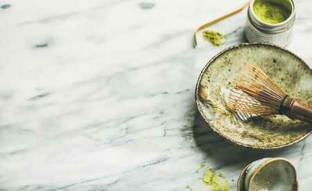 Flat-lay of Japanese tools for brewing matcha green tea. Matcha powder in tin can, Chashaku spoon, Chasen bamboo whisk, Chawan bowl over grey marble background, selective focus, copy spaceの写真素材