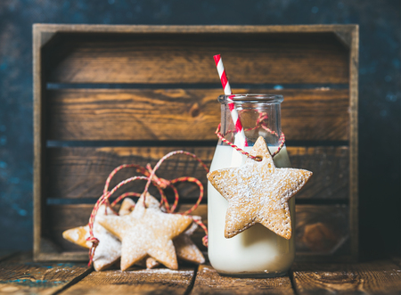 Christmas festive gingerbread star shaped cookies and bottle with milk and straw, wooden tray at background. Selective focus, copy space, horizontal compositionの写真素材