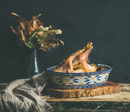 Roasted whole chicken for Christmas eve celebration table on rustic wooden board, black wall background, copy space, square cropの写真素材