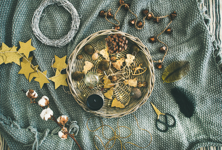 Preparing for Christmas. Flat-lay of holiday decoration toys, garlands, lights, wreath over grey winter bed blanket, top view.の写真素材