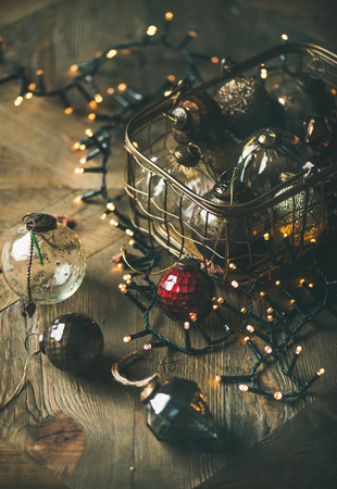 Christmas or New Year background. Christmas tree toy decoration glass balls in vintage box and light garland over rustic wooden background, selective focusの写真素材