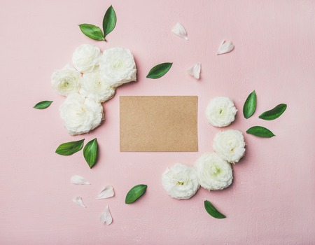 Floral background with blank card in center. Flat-lay of white ranunculus flowers over light pink background, top view, copy space. Greeting card for Womens day, Easter or wedding invitationの写真素材