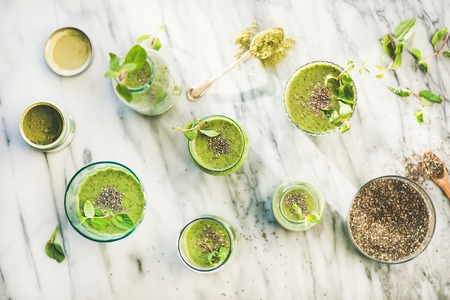 Matcha green vegan smoothie with chia seeds and fresh mint in glasses and bottles over marble background, top view. Clean eating, detox, alkaline diet, weight loss food conceptの写真素材