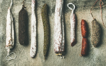 Variety of Spanish or Italian cured meat sausages. Flat-lay of fuets and salamies over rough grey concrete background, top viewの写真素材