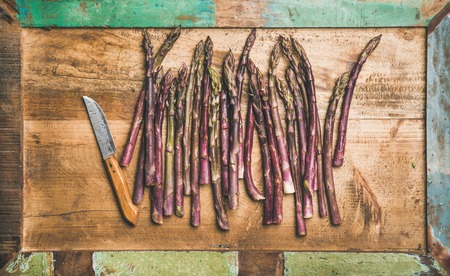Seasonal harvest produce. Flat-lay of fresh raw uncooked purple asparagus in row over wooden tray background, top view. Local market food conceptの写真素材