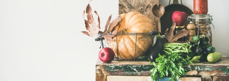 Autumn seasonal food ingredients, kitchen utensils. Vegetables, pumpkin, apples, canned food, fallen...