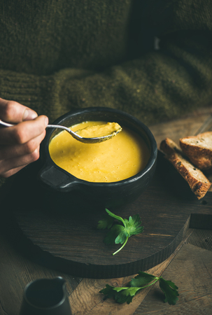 Man in dark winter sweater eating sweet corn and shrimp chowder soup from bowl with toasted bread. Autumn or winter warming foodの写真素材
