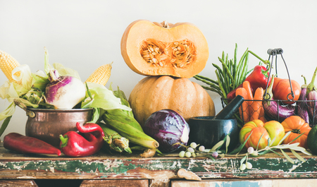 Fall vegetarian food ingredient variety. Assortment of various Autumn vegetables for healthy cooking over wooden rustic cupboard, white wall background. Local market organic produceの写真素材