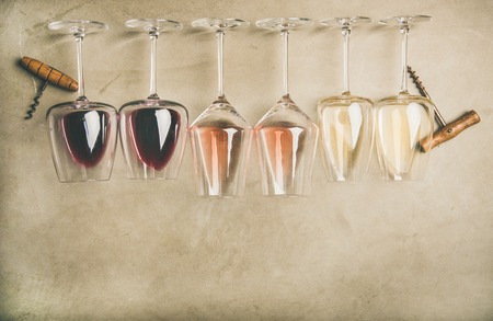 Flat-lay of red, rose and white wine in glasses in row and corkscrews over grey concrete background, top view, wide composition. Wine bar, winery, wine degustation conceptの写真素材