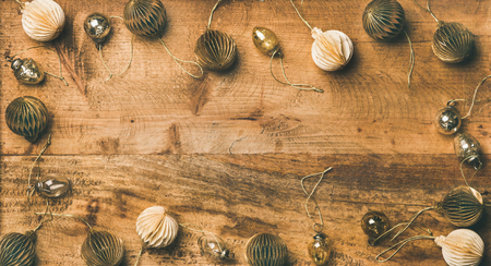 Christmas, New Year holiday background, texture, wallpaper. Flat-lay of paper white and golden christmas tree decoration toys and glass balls over rustic wooden background, top view, copy spaceの写真素材