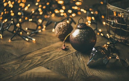 Christmas or New Year background. Vintage Christmas tree toy decoration balls and light garland over rustic wooden background, selective focus, copy spaceの写真素材
