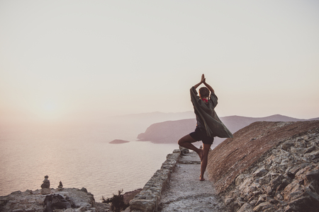 Young woman tourist standing and meditating on ancient stones of Monolithos castle in Rhodes island, Greece, at sunset on clear summer dayの写真素材