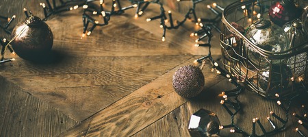 Christmas or New Year background. Vintage Christmas tree toy decoration balls in box and light garland over rustic wooden background, selective focus, copy space, horizontal compositionの写真素材