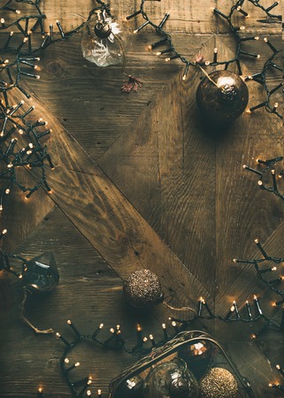 Christmas or New Year background. Holiday preparation flat-lay. Vintage Christmas tree toy decoration balls and light garland over rustic wooden background, top view, copy space, vertical compositionの写真素材