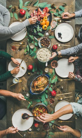 Traditional Christmas, New Year holiday celebration. Flat-lay of friends or family eating at festive table with turkey or chicken, vegetables, mushroom sauce, fruit, top view, vertical compositionの写真素材