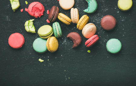 Flat-lay of sweet colorful French macaron cookies over black background, top view, copy spaceの写真素材