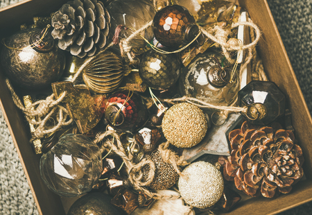 Christmas or New Year preparation. Flat-lay of vintage Christmas tree decoration toys, balls and pine cones in wooden box over grey knitted blanket background, top view, close-up. Festive holiday moodの写真素材