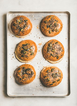 Flat-lay of freshly baked homemade whole grain gluten-free buns with seeds for cooking burgers, top viewの写真素材