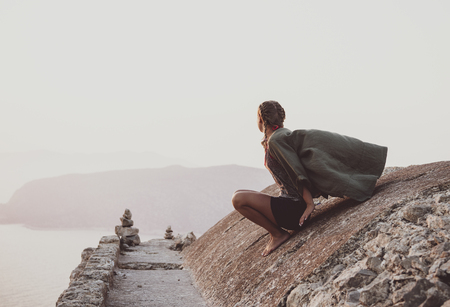 Young woman tourist sitting and looking at horizon on ancient stones of Monolithos castle in Rhodes island, Greeceの写真素材