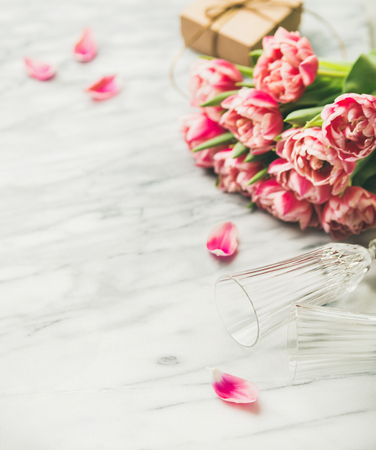 Bouquet of pink tulips and gift box with ribbon over white marble tableの写真素材