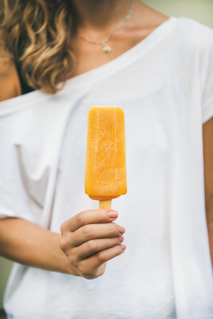 Healthy vegan orange mango citrus ice cream  in hand of young woman.の写真素材