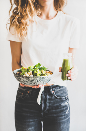Woman in jeans standing and holding vegan superbowl or Buddha bowl with hummusの写真素材