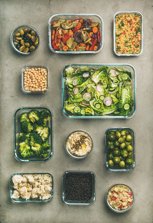 Healthy vegan dishes in containers. Flat-lay of vegetable salads, legumes, beans, olives, sprouts, hummus dip, couscous for take-away lunch, top view, vertical composition. Spring menu, clean eatingの写真素材