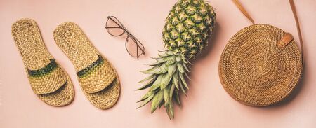 Variety of summer apparel items. Flat-lay of summer flip flops, sunglasses, wicker shoulder bag and...