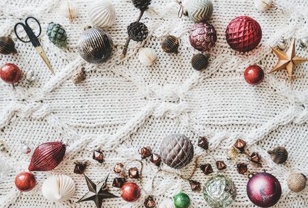 Christmas or New Year holiday background, texture, wallpaper. Flat-lay of Christmas festive decoration toys over white knitted woolen background, top view, copy space. Preparation for winter holidaysの写真素材