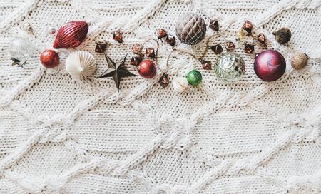 Christmas or New Year holiday background, texture, wallpaper. Flat-lay of Christmas festive decoration toys and balls over white knitted woolen background, top view, copy spaceの写真素材