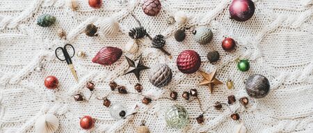 Christmas or New Year holiday background, texture, wallpaper. Flat-lay of Christmas glass festive decoration toys and balls over white knitted woolen background, top view, wide compositionの写真素材