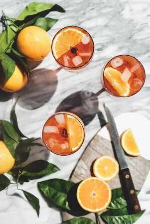 alcohol cold drink in glasses with oranges and ice cubes over grey marble table, top view. Summer refreshing drink conceptの写真素材