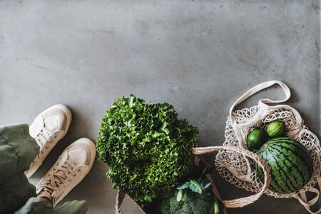Eco-friendly lifestyle. Flat-lay of of grocery jute and net bags with fresh organic vegetables, greens, fruit from local farmers market, copy space. Zero waste, healthy, vegan and clean eating conceptの写真素材