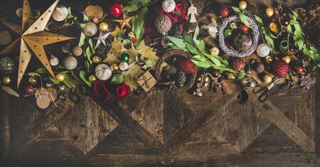 Christmas, New Year holiday layout background, texture or wallpaper. Flat-lay of decorative objects, fur tree toys, garlands, ropes, candles, glass balls, wreaths over wooden background, copy spaceの写真素材