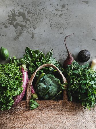 Bag with healthy grocery goods. Flat-lay of jute bag full of vegetables, greens from local farmers market over concrete kitchen counter, top view, copy space. Eco-friendly, zero waste, vegan conceptの写真素材