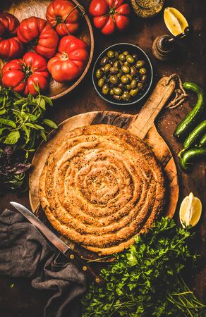 Turkish traditional pastry for breakfast or as starter. Flat-lay of Turkish borek pie with spinach filling and vegetable ingredients over rusty table background, top view. Turkish traditional cuisineの写真素材