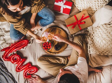 Young happy couple sitting on blankets in bed at homeの写真素材