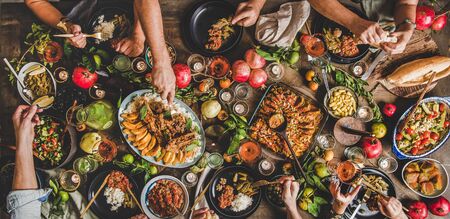 Flat-lay of family feasting with Turkish cuisine lamb chops, quince, bean, vegetable salad, babaganush, rice pilav, pumpkin dessert, lemonade over rustic table, top view, wide compositionの写真素材