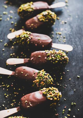 Chocolate glazed ice cream pops with pistachio icing over darkの写真素材