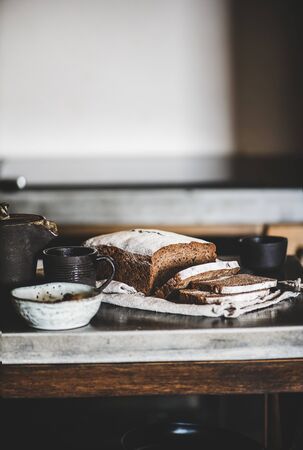 Healthy rye Swedish bread loaf cut in slices covered with flour with vintage knife on cotton towel over kitchen counter, selective focusの写真素材