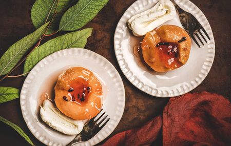 Flat-lay of Turkish traditional dessert with sweet quince boiled in sugar syrup and spices and heavy cream Kaymak on white plates over rusty brown table background, top view. Turkish national cuisineの写真素材