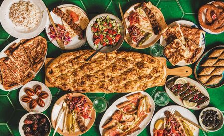 Muslim Ramadan iftar family dinner arrangement. Flat-lay of Middle East table with dates, dolma, kebab, flatbread, pide, borek, sweets, salad, top view, copy space. Ramazan fasting Turkish cuisineの写真素材