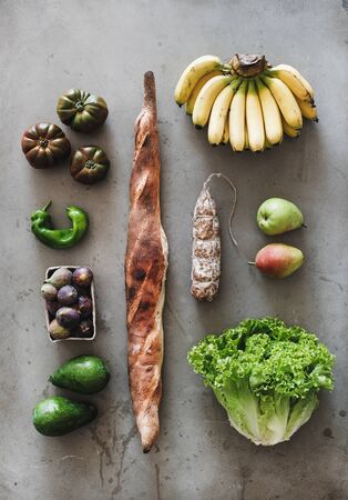 Flat-lay of healthy fresh vegetables, fruits, greens, freshly baked bread and sausage over grey concrete background, top view. Local farmers market conceptの写真素材