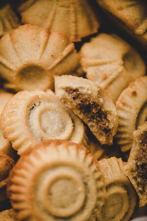Close-up of Turkish Hatay semolina cookies with date, fig, walnut filling in metal form and wooden cookie baking molds over rusty background. Middle East regional east Anatolian cuisineの写真素材