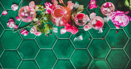 Summer refreshing cold beverage drink. Flat-lay of rose lemonade with ice in glasses and rose flower...