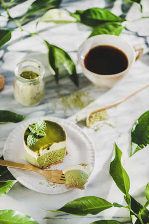 Coffee and dessert setup. Green matcha cheesecake and black coffee in cup over grey marble table background, selective focus. Healthy, vegan, vegetarian, low calorie food conceptの写真素材