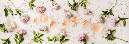 Rose wine variety layout. Flat-lay of rose wine in glasses with peony flowers over white background, top view. Summer drink for party, wine shop or wine tasting conceptの写真素材