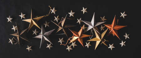 Christmas or New Year holiday texture, wallpaper and background. Flat-lay of colorful paper toy decorative stars of different sizes over black background, top view, copy space, wide compositionの写真素材